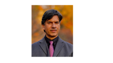 This image shows a headshot of Steven Lutzky in a grey suit with a pink tie and black dress shirt. 