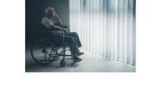photo of an older Asian man with grey hair and glasses sitting in a wheelchair looking out a window