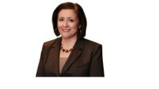 color photo of Laura Vegas, a young white woman with shoulder-length brown hair wearing a black suit