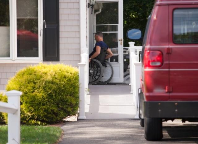 man in wheelchair going into house